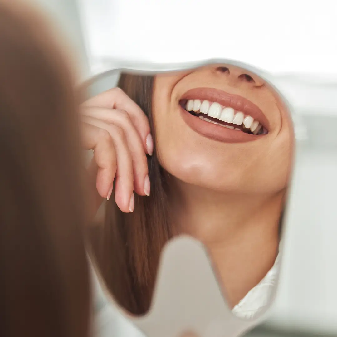 An Image Of A Face Of A Woman Looking At The Mirror, Where Only Her Teeth Are Showcased