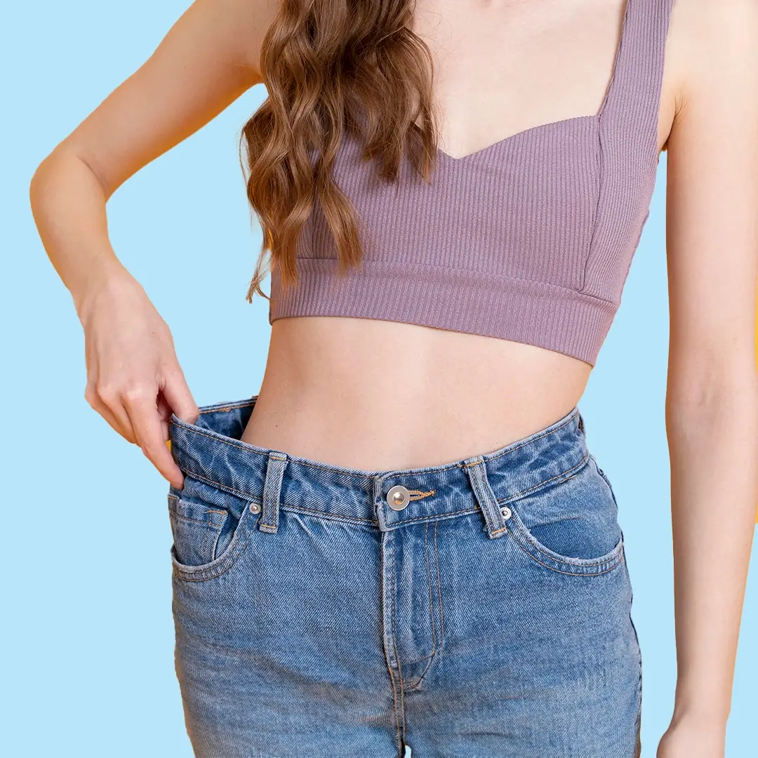 A Young Slim Woman In Jeans Holding Her Old Big Jeans After She Lost Much Weight